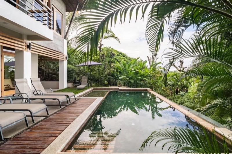 Pool and sun loungers beside a house surrounded by tropical plants at Casas De Soleil