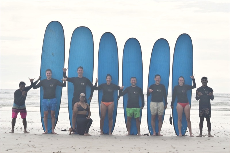 Surf lesson group standing with their boards on the beach with Del Soul Surf School