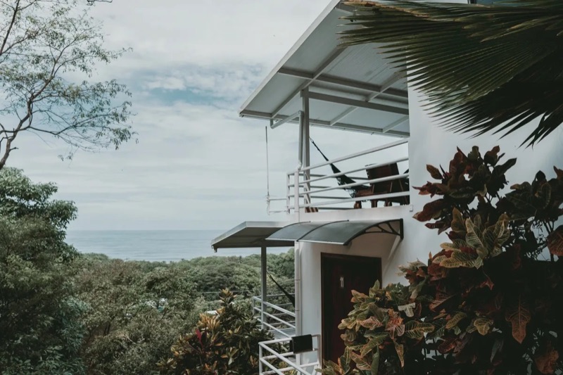 Lodge building with balconies and an ocean view through the trees at Funky Monkey Lodge