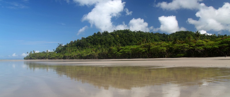 The long, flat sand of Playa Hermosa reflecting the sky