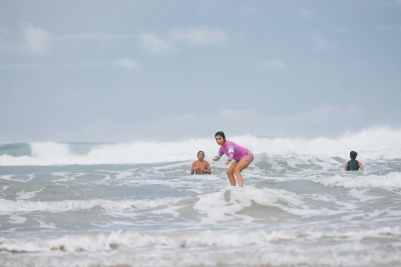 Surf student standing up in the whitewater while instructors watch, Shaka Costa Rica
